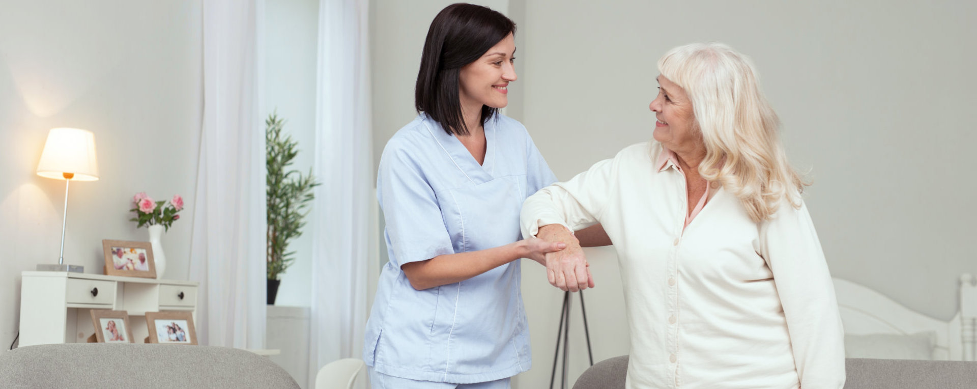 Unpaid work. Cheerful caregiver helping senior woman who smiling