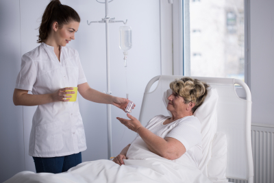 nurse giving medicine to senior woman